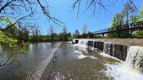 Small waterfall flowing over a dam in sunny spring forest, 4K Stock Footage 340508055