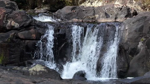 Small Waterfall Flowing Over Dark Rocks, Static Shot Stock Footage 343882958