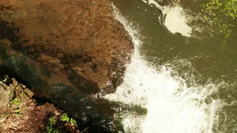 Small waterfall flowing over huge rock into a pond Stock Footage 153871129