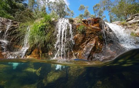 Small waterfall flowing in a river split level view over under water Foto stock