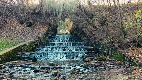Small Waterfall Flowing Through Stone Steps in Autumn Forest Video stock 320710585