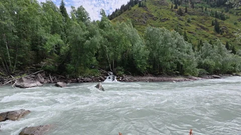 Small waterfall flowing into the turquoise waters of the Koksu River Stock Footage 330182632