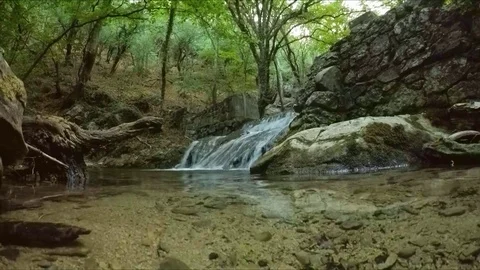 A small waterfall flows from an abandoned stone wall. Video stock 84786769