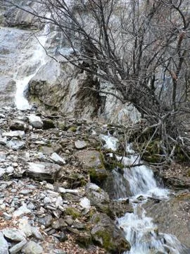 Small waterfall flows down from the cliff Stock Photos