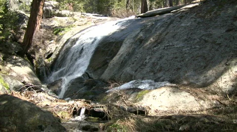 Small waterfall flows down the rocks into a creek Stock Footage 365265
