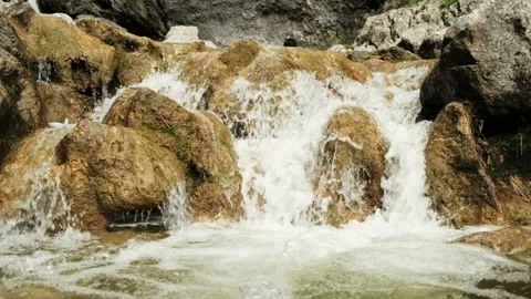 Small waterfall flows into a pool with bubbles forming in slow motion Stock Footage 136419856