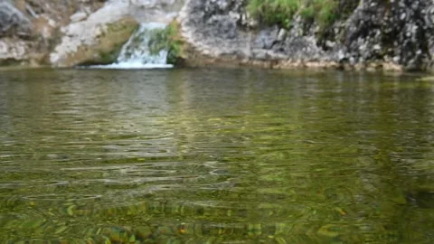A small waterfall flows into a pool of a mountain river (slow motion) Stock Footage 212735038
