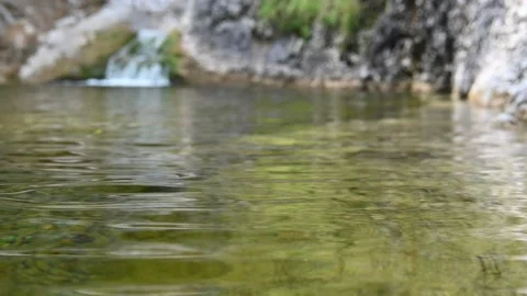 A small waterfall flows into a pool of a mountain river and creates waves (slow) 스톡 동영상 212735309