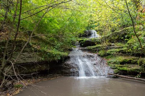 A small waterfall flows into the river Stock Photos