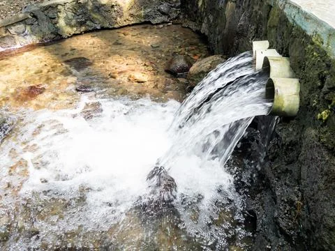 A Small Waterfall Flows Through Three Pipes Stock Photos