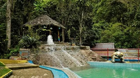 A small waterfall is in front of a hut Stock Photos