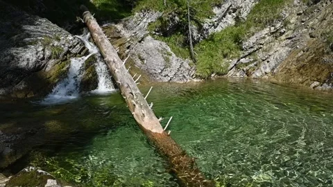 A small waterfall from a mountain stream runs into a pool (slow motion) Video stock 260843150