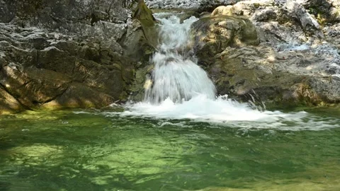 A small waterfall from a mountain stream runs into its pool 스톡 동영상 260844083