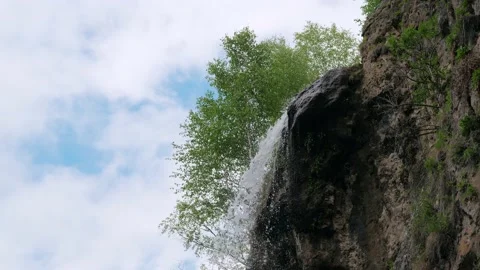 Small waterfall in mountains against background of white clouds and blue sky. Stock Footage 171233770