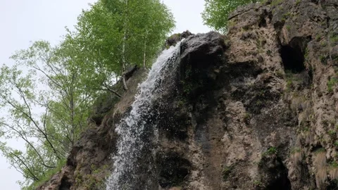 A small waterfall in the mountains flows into a small mountain river. 4K Stock Footage 170851414