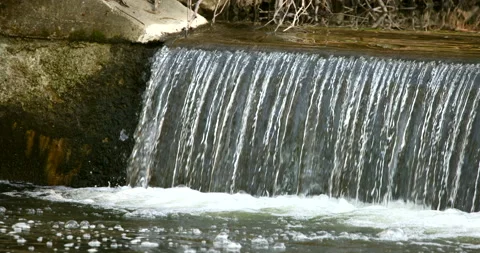 Small waterfall on a narrow river in a suburban neighborhood with flowing water Stock Footage 195893010