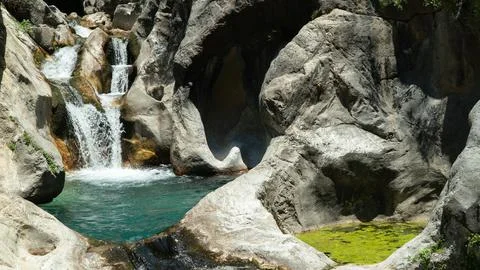 Small waterfall with a natural pool inside the mountains Stock Photos