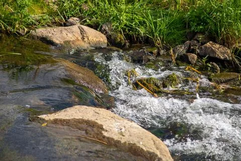 A Small waterfall next to a rock through a small stream Stock Photos