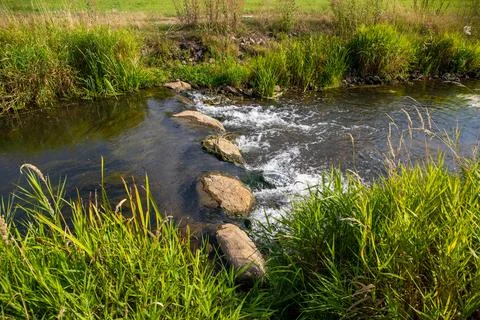 A Small waterfall next to a rock through a small stream Stock Photos