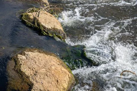 A Small waterfall next to a rock through a small stream Stock Photos