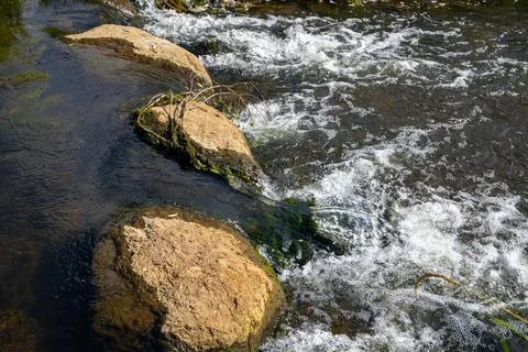 A Small waterfall next to a rock through a small stream Stock Photos