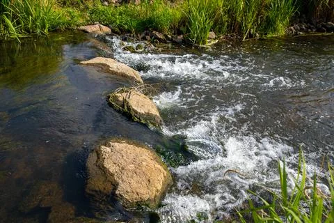 A Small waterfall next to a rock through a small stream Stock Photos