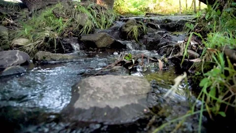 Small waterfall or cascade captured near the water surface full of rocks and pla Stock Footage 104974098