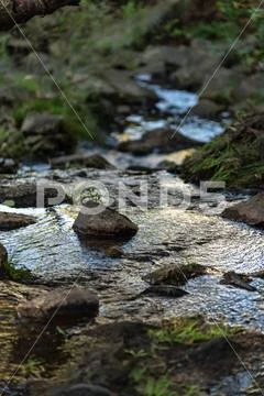 Small waterfall or cascade captured near the water surface full of rocks and Stock Photos