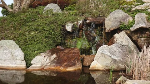 A small waterfall in the park area evokes a feeling of calm and satisfaction. Stock Footage 241242165