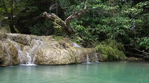 A Small Waterfall Pours Water Into an Emerald Pool of Water Stock Footage 74292130