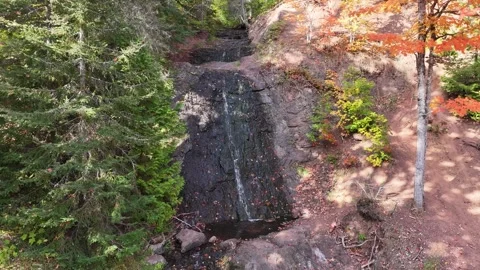 Small Waterfall Running Through Red Rock With Vibrant Autumn Colors Aerial Stock Footage 315265435