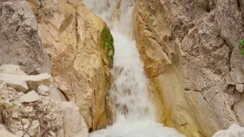 Small waterfall surrounded by gold colored stones Stock Footage 283571302