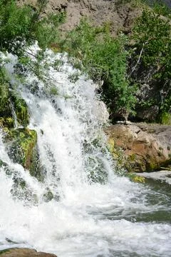 Small waterfall surrounded by mossy rocks, horizontal photo summer day with t Stock Photos