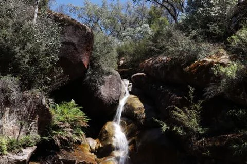Small waterfall surrounded by rocks and trees Stock Photos