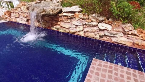 Small waterfall at swimming pool in a resort Stock Footage 76470803