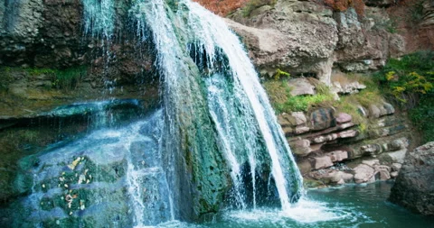 Small waterfall. Tilt down to reveal woman standing in water. Slow motion. 8K Vídeo Stock 255811000