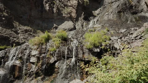 Small waterfall trickling over rock cliff in Colorado mountains Video stock 348025271