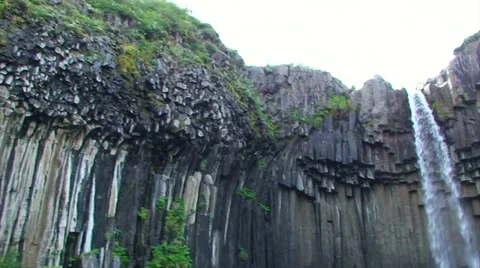 Small waterfall on volcanic rock back lit, pan right from lower angle. Stock Footage 38020663