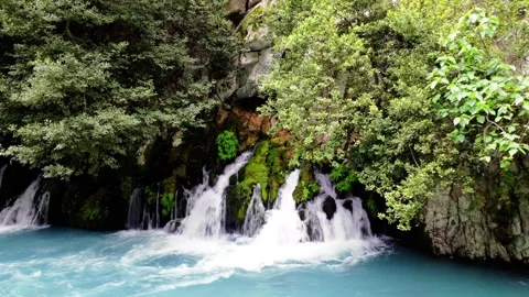 Small waterfalls flow into fast turquoise mountain river, creating a continuous Vídeos de archivo 275559981
