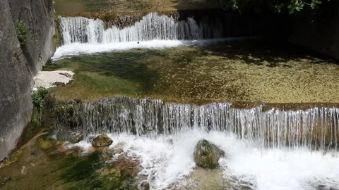 Small waterfalls formed by a river that flows into an artificial canal Stock Footage 154458051