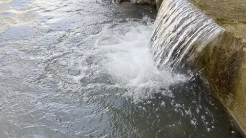 Small waterfalls from under a bridge on a mountain river, late morning. Stock Footage 330498571