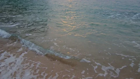 Small wave on the beach with sunrise reflected in the water, in Spain Stock Footage 230096298