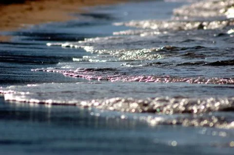 Small wave crashing down on sandy beach Stock Photos