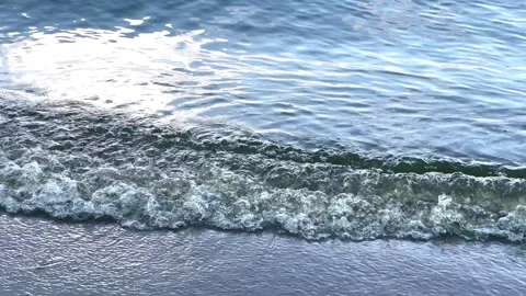 A small wave gently washes onto the sandy shore. Stock Footage 281519158