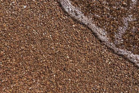 A small wave running on a sandy beach. Background for a banner on tourism and Stock Photos