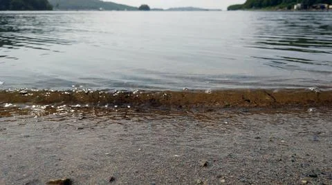 Small wave on a sandy shore during calm weather Stock Photos