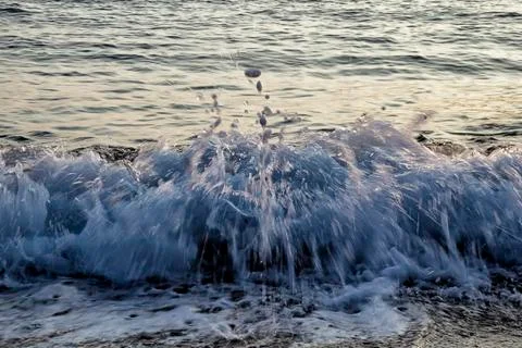 Small wave splash with blurred drops at sandy beach Stock Photos