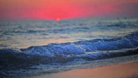 Small wave washing ashore during vibrant sunset, calming cinematic 4K footage. Stock Footage 335490535