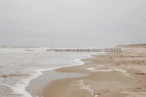 Small waves and beach on a cloudy day Stock Photos