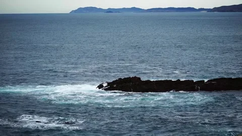Small waves from the Atlantic Ocean crash onto rocks jutting out of the water Stock Footage 303245796
